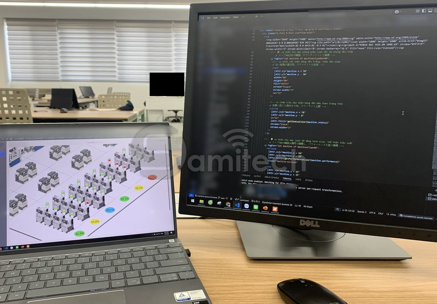 Bàn làm việc: màn hình lớn hiện mã nguồn dựng sơ đồ mặt bằng, laptop bên cạnh chạy chính sơ đồ đó với chấm trạng thái từng máy.
